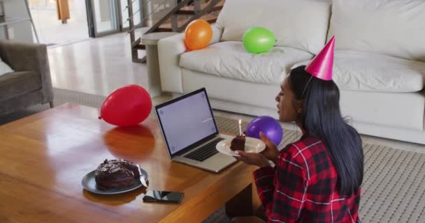 Mixed race woman using laptop having birthday video chat holding a cake — Stock Video