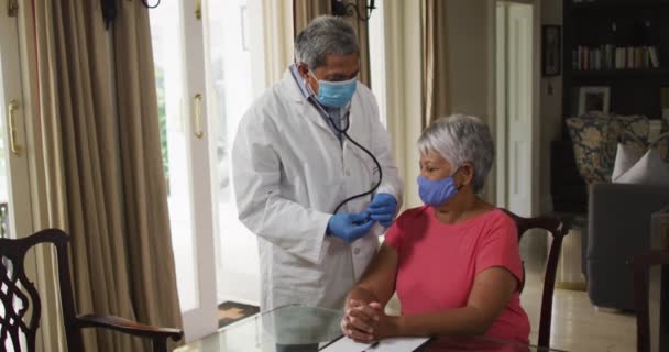 Мужчина-врач, посещающий пожилую женщину смешанной расы со стетоскопом — стоковое видео