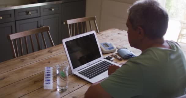 노인 혼혈 남성 노트북을 사용하여 온라인 의료 상담을 받고 있다 — 비디오