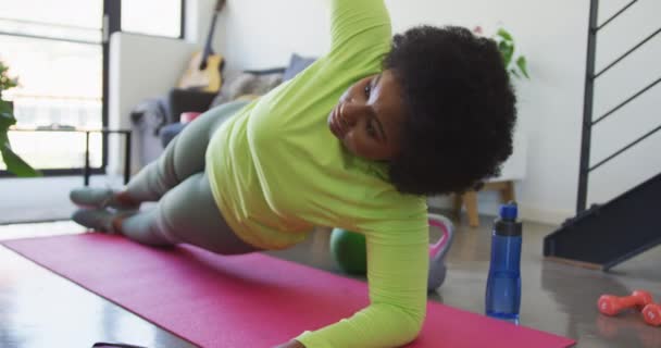 Vlogger mujer afroamericana acostada en una alfombra de ejercicio haciendo ejercicio — Vídeos de Stock