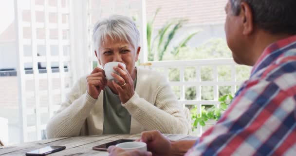 Щаслива старша змішана пара гонок, що розмовляє кавою в саду — стокове відео