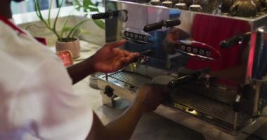 Afrika kökenli Amerikalı erkek barista kahve makinesinde kahve yapıyor.