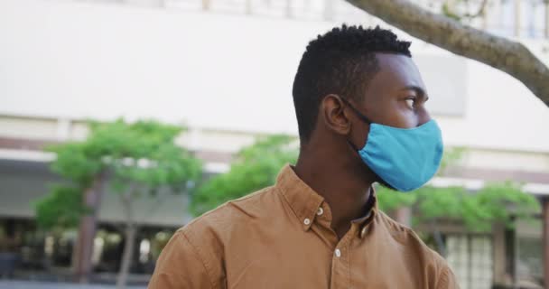 African american businessman wearing face mask sitting in park — Stock Video