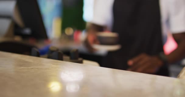 Środkowa część afrykańskiego mężczyzny barista serwującego kawę w brązowej filiżance kawy — Wideo stockowe