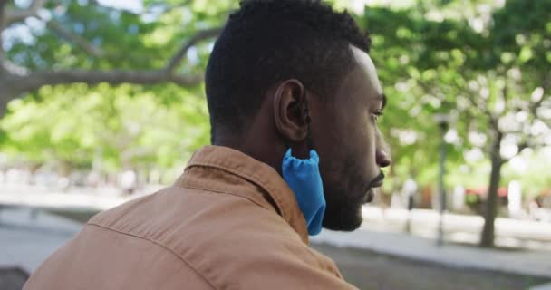 Homme d'affaires afro-américain avec masque facial buvant du café dans le parc — Video