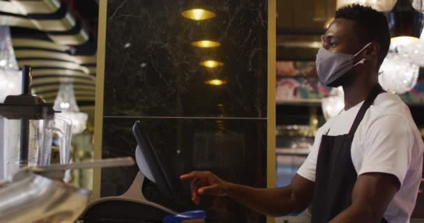 Αφροαμερικάνος barista φορώντας μάσκα προσώπου χρησιμοποιώντας μέχρι — Αρχείο Βίντεο