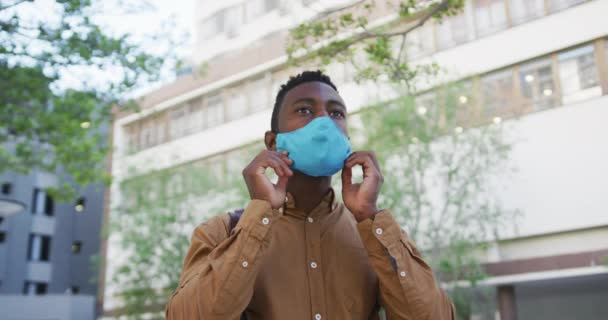Африканский бизнесмен настраивает маску для лица стоя на улице — стоковое видео
