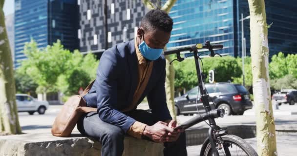 Afrikai-amerikai üzletember visel arc maszk sms-ezés okostelefon az utcán — Stock videók