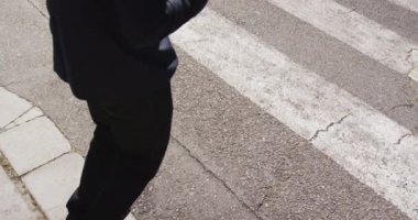 Afro-Amerikan işadamının, Zebra geçidinden geçerken elinde kahve taşıyan alt kesimi.