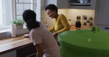 Karışık ırk lezbiyen çifti ve kız temizleme mutfağı. Coronavirus covid 19 salgını sırasında evde tek başına vakit geçirmek..