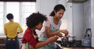 Karışık ırk lezbiyen çifti ve kızı mutfakta yemek hazırlıyorlar. Coronavirus covid 19 salgını sırasında evde tek başına vakit geçirmek..