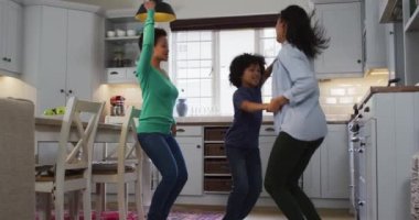 Karışık ırk lezbiyen çifti ve kızı mutfakta dans ediyor. Coronavirus covid 19 salgını sırasında evde tek başına vakit geçirmek..