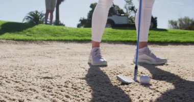 İki beyaz kadın golf oynuyor. Biri sığınaktan ateş ediyor.