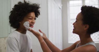 Karışık ırk anne ve kızı tuvalette eğleniyor. Kızının yüzüne krem sürüyorum. Coronavirus covid 19 salgını sırasında evde tek başına vakit geçirmek..