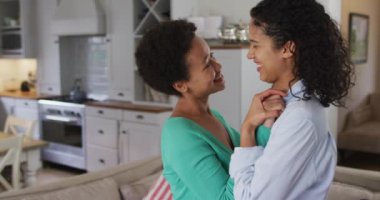 Oturma odasında dans eden romantik melez lezbiyen çift. Coronavirus covid 19 salgını sırasında evde tek başına vakit geçirmek..