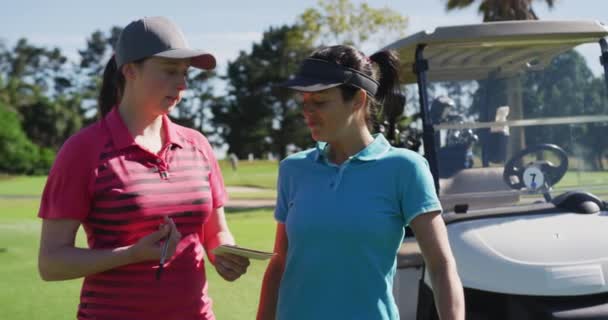 Deux femmes caucasiennes jouant au golf parlant écriture dans le carnet — Video