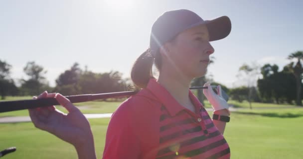 Retrato de una jugadora de golf caucásica sonriendo mientras estaba de pie con un palo de golf a su espalda — Vídeos de Stock