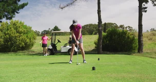 Дві білошкірі жінки грають в гольф, один знімається з бункера — стокове відео