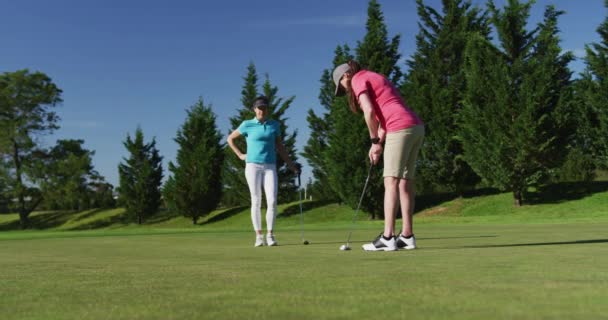 Two caucasian women playing golf one taking shot from bunker — Stock Video