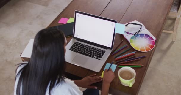 Mujer de raza mixta utilizando la escritura portátil en portátil beber café trabajando desde casa — Vídeos de Stock