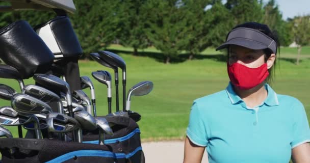 Mulher branca jogando golfe usando máscaras faciais levando um taco de golfe — Vídeo de Stock