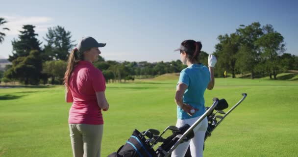 Δύο καυκάσιες γυναίκες παίκτες του γκολφ μιλούν στέκεται στο γήπεδο του γκολφ — Αρχείο Βίντεο