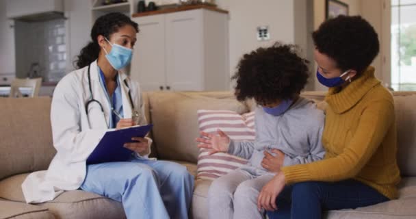 Ras campuran dokter wanita memakai masker memeriksa ras campuran gadis di rumah — Stok Video