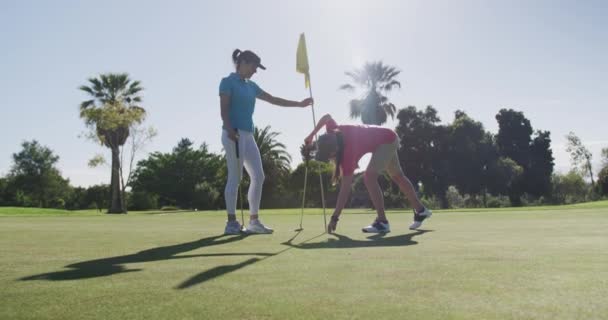 Dos mujeres caucásicas jugando al golf una alcanzando la pelota — Vídeos de Stock