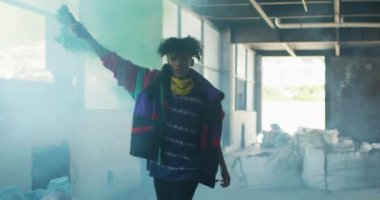 Mavi işaret fişeği tutan melez bir adam boş bir binada koşuyor.