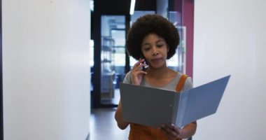 Karışık ırk işkadını modern ofiste evrak işleriyle uğraşıyor.