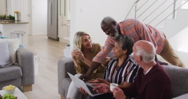 İki farklı son sınıf çifti bir kanepede oturmuş dizüstü bilgisayar kullanıyor ve gülüyorlar. Üst düzey emeklilik hayatı arkadaşları sosyalleşiyor.