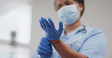 Kıdemli Afro-Amerikan kadın doktor yüz maskesi takıyor koruyucu eldiven takıyor. Koronavirüs covid 19 salgını sırasında sağlık hizmetleri hijyen koruması.