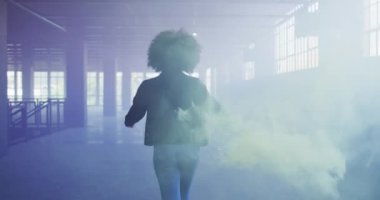 Elinde yeşil işaret fişeği olan melez bir kadın boş binada yürüyor.