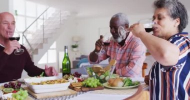 Masanın başında oturan, şarap içen ve akşam yemeği yiyen farklı yaşlı çiftler. Huzurevinde sağlık hizmetleri.