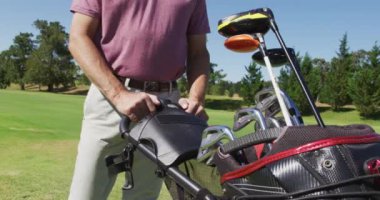 Güneşli bir günde golf sahasında golf çantasıyla yürüyen beyaz bir adam. emeklilik sporları ve aktif yaşlı yaşam tarzı.