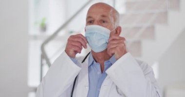 Kameraya bakarken maske takan Kafkas erkek doktorun portresi. Koronavirüs covid 19 salgını sırasında sağlık hizmetleri hijyen koruması.