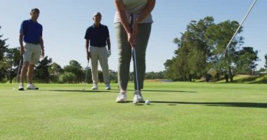 Güneşli bir günde golf sahasında golf topunu deliğinden çıkaran beyaz bir kadın. emeklilik sporları ve aktif yaşlı yaşam tarzı.