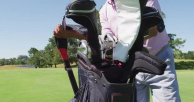 Güneşli bir günde golf sahasında golf çantasıyla yürüyen beyaz bir adam. emeklilik sporları ve aktif yaşlı yaşam tarzı.