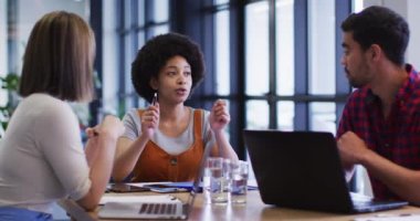 Çeşitli iş adamları modern ofiste bilgisayarlarını kullanarak evrak işlerini hallediyorlar.