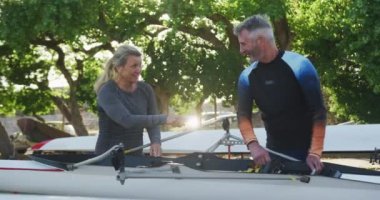 Beyaz adam ve kadın, su için kayık hazırlıyorlar. spor emekliliği hobileri sağlıklı açık hava yaşam tarzı kürek çekiyor..