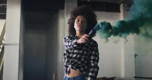 Smíšené rasy žena drží zelenou světlici stojící v prázdné budově — Stock video