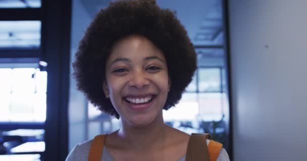 Carrera mixta mujer de negocios caminando mirando a la cámara y sonriendo en la oficina moderna — Vídeos de Stock