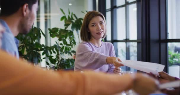 Diverse business people sitting using laptops going through paperwork in office — Stock Video