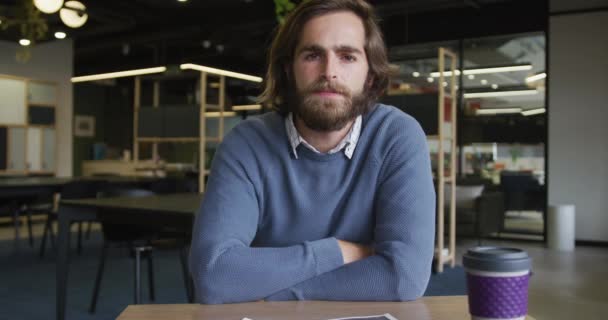 Caucásico hombre de negocios teniendo un video chat sosteniendo una taza de café en la oficina moderna — Vídeo de stock