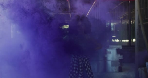 Sekarotuinen nainen seisoo sinisessä valoraketissa tyhjässä rakennuksessa — kuvapankkivideo