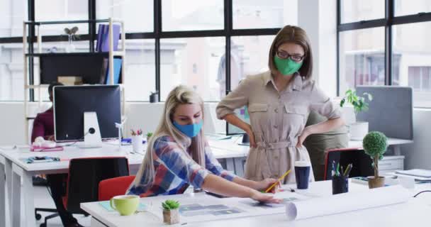 Divers collègues de bureau féminines portant des masques faciaux discutant du plan directeur au bureau moderne — Video