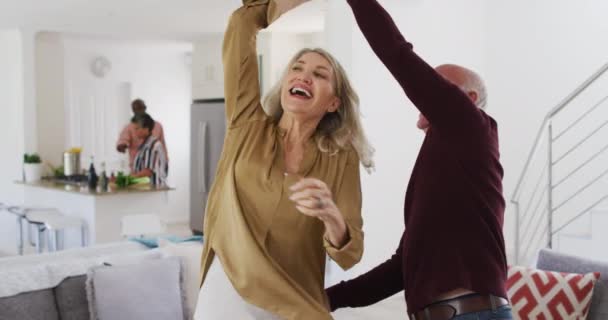 白人老年夫妇在客厅里跳舞 背景是非洲裔老年夫妇 老年退休生活朋友社交活动 — 图库视频影像