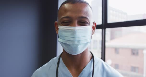 Ritratto di medico maschio di razza mista che indossa una maschera che guarda la fotocamera e sorride — Video Stock