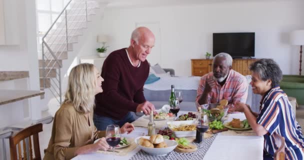 テーブルドリンクワインのそばに座って夕食を食べる多様なシニアカップル 老人ホームでの健康フィットネス — ストック動画