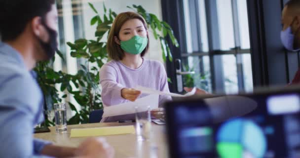 Διαφορετικοί επιχειρηματίες που φορούν μάσκες προσώπου κάθονται χρησιμοποιώντας φορητούς υπολογιστές που περνούν από τη γραφειοκρατία στο γραφείο — Αρχείο Βίντεο